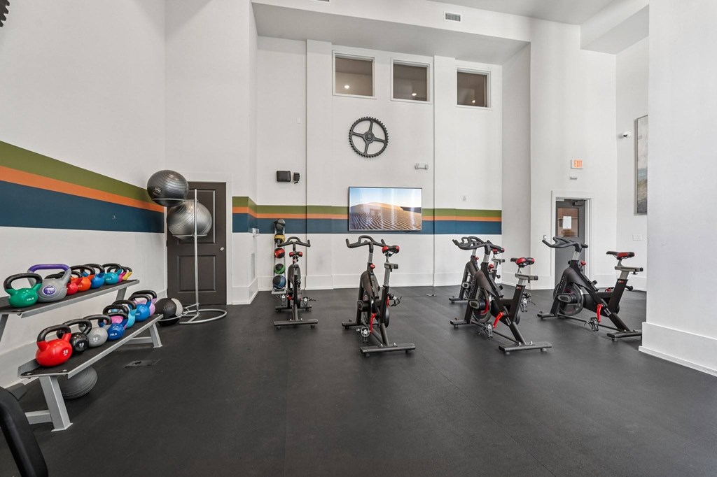 A gym with Matrix exercise bikes, kettlebells, weighted balls, and  exercise balls